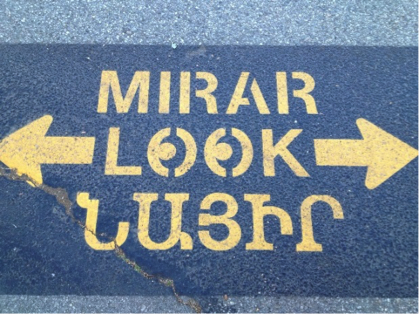 painted sidewalk sign with the word look in Spanish, English and Armenian