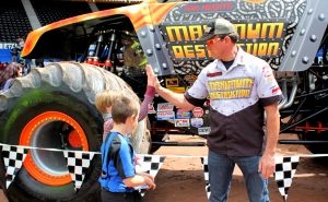 Photo of a monster truck driver giving a high five to a young boy