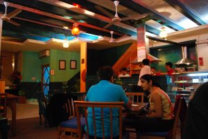 A man and a woman are shown talking at a table in a cafe.