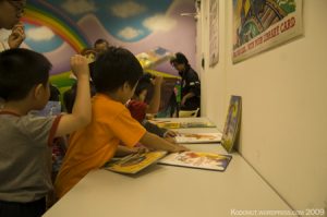 Young students looking at books at a table.